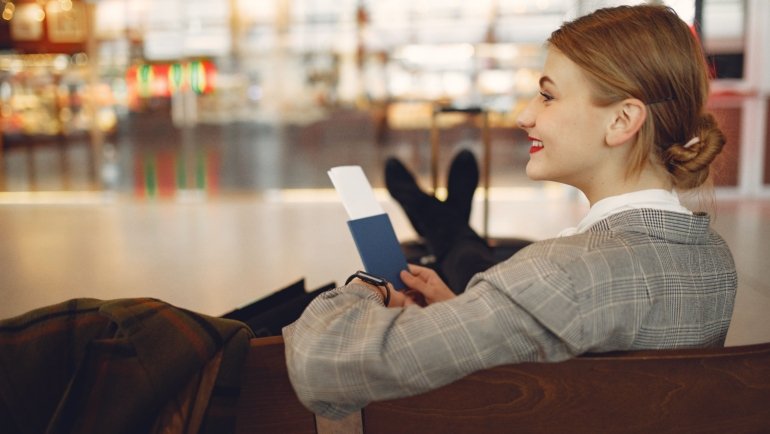 Traveler wearing a secure and comfortable travel neck pouch in an airport setting, holding passport and phone