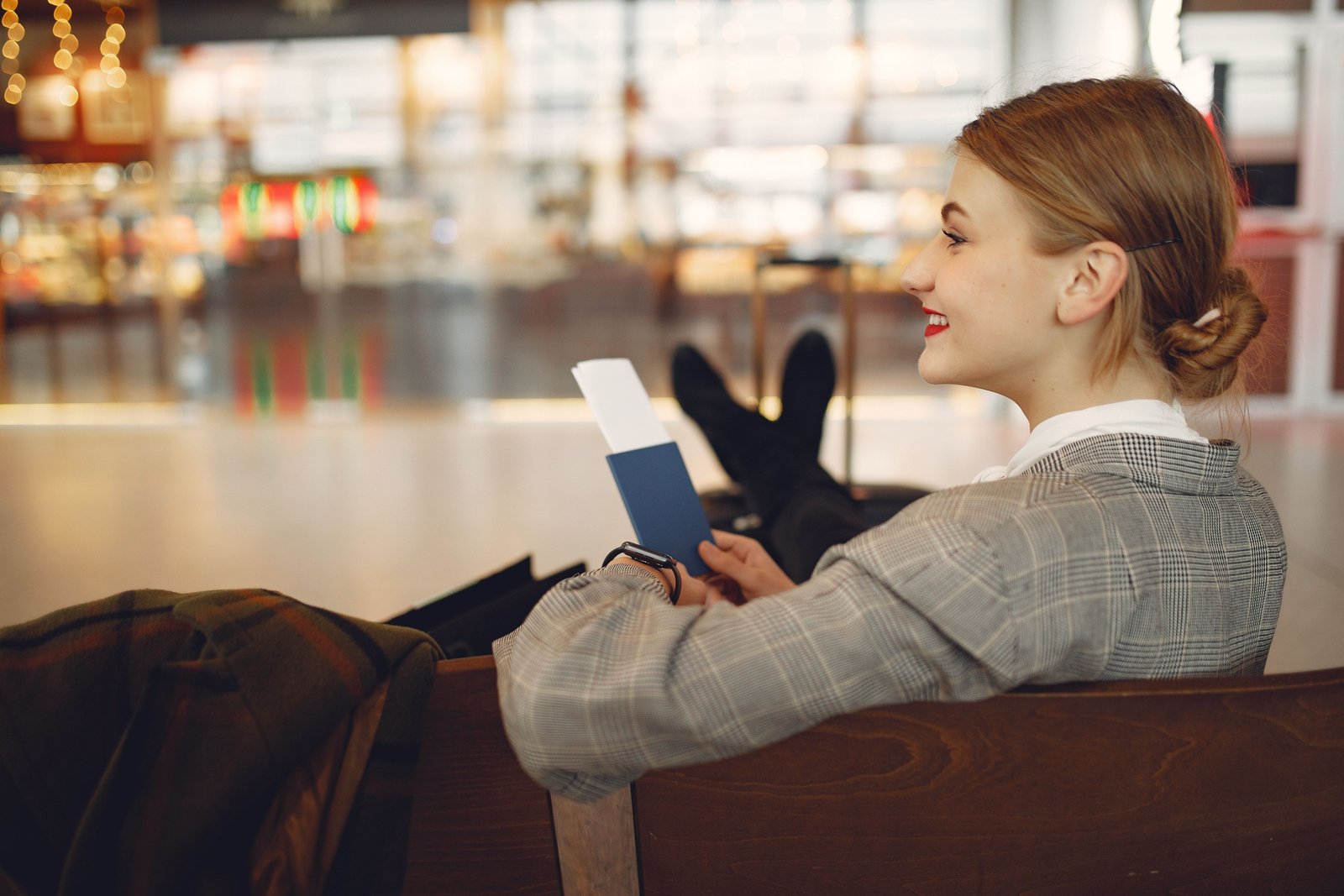 Traveler wearing a secure and comfortable travel neck pouch in an airport setting, holding passport and phone