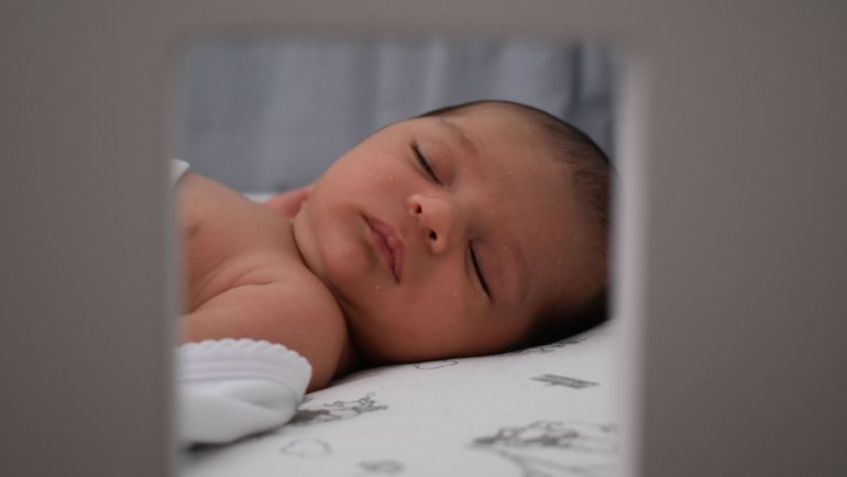 Baby peacefully sleeping on a comfortable and safe travel crib mattress during a family trip