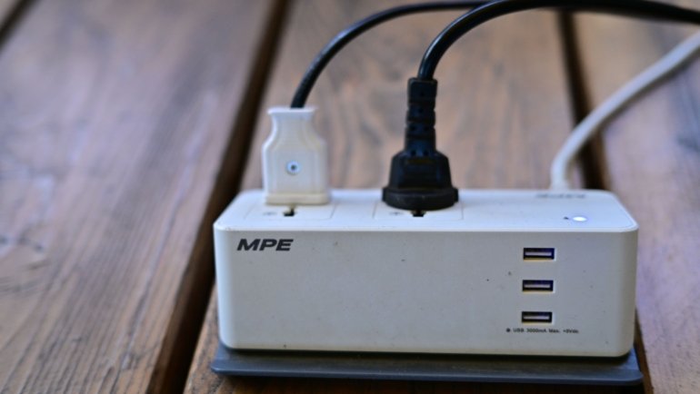Compact 5 in 1 travel power strip charging multiple devices including smartphone, laptop, and camera safely on the go