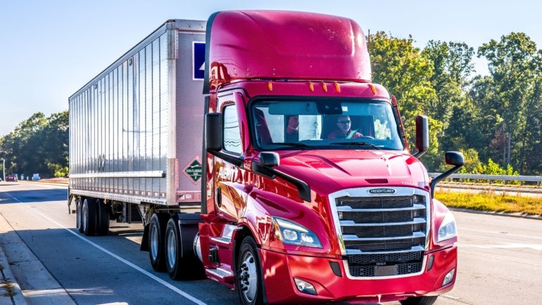 Fully loaded tractor-trailer truck traveling on the highway at 55 mph demonstrating safety and fuel efficiency