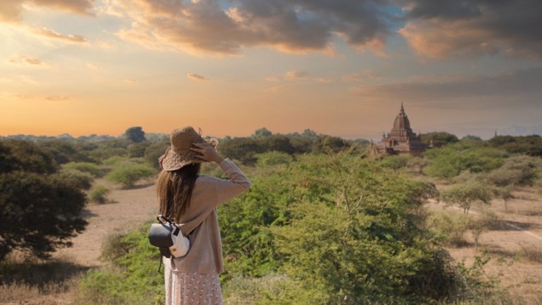 Traveler holding travel insurance documents in Myanmar with landmarks in the background symbolizing protection and peace of mind