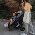 Parent pushing a compact lightweight travel stroller with child facing parent, showcasing bonding and easy maneuverability during travel