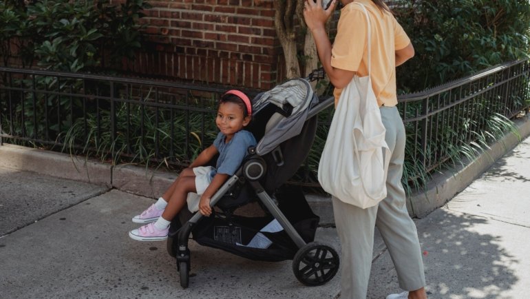 Parent pushing a compact lightweight travel stroller with child facing parent, showcasing bonding and easy maneuverability during travel