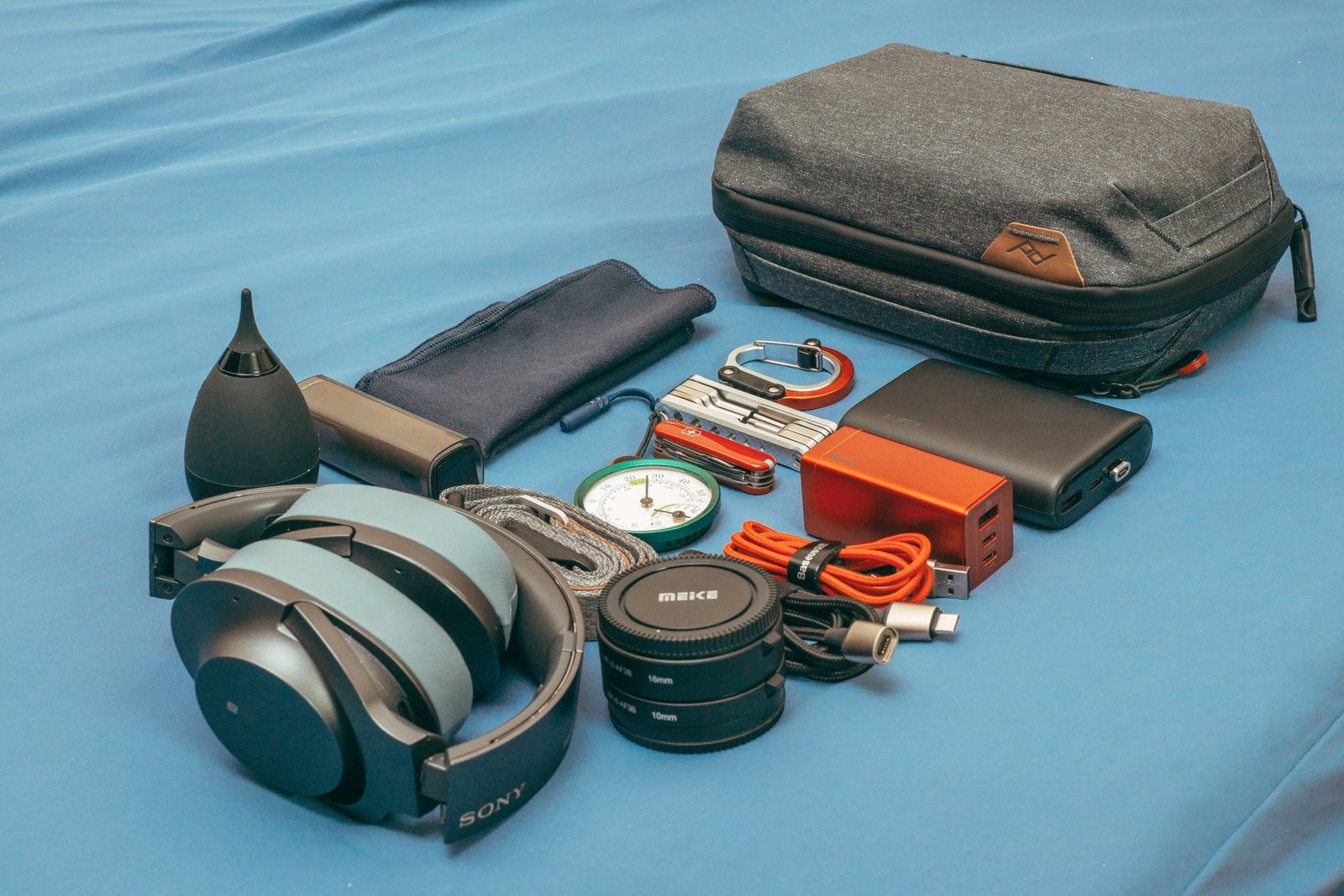 Open snapback travel case with organized electronic gadgets and accessories inside, showcasing compact and secure travel storage