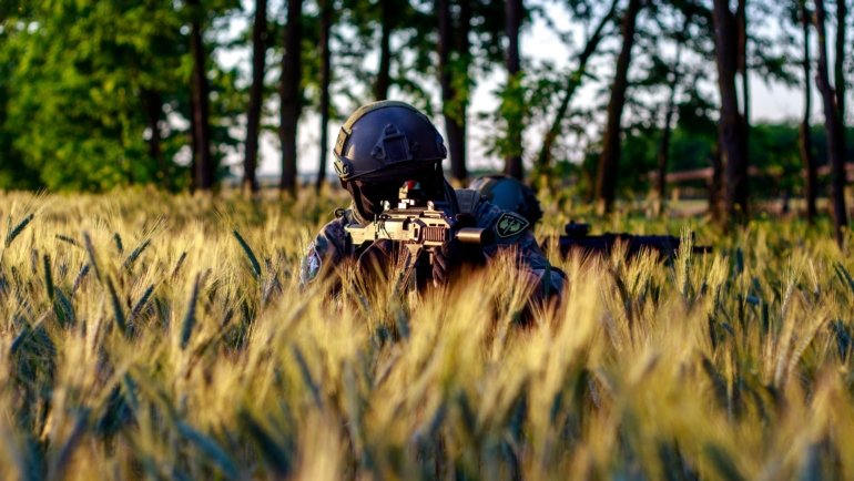 Airsoft player shooting 0.2g BB from gun outdoors with focus on accuracy and range