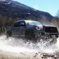 First generation Toyota Tacoma equipped with long travel suspension driving over rocky off-road trail
