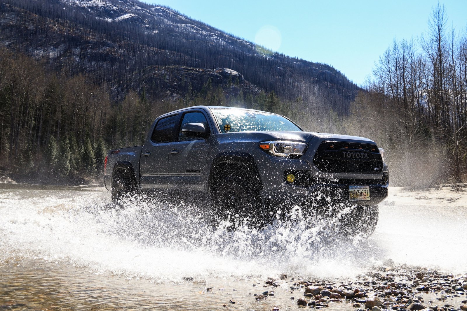 First generation Toyota Tacoma equipped with long travel suspension driving over rocky off-road trail