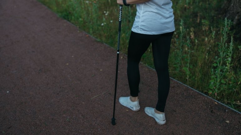 Traveler using a collapsible walking stick for support while hiking outdoors