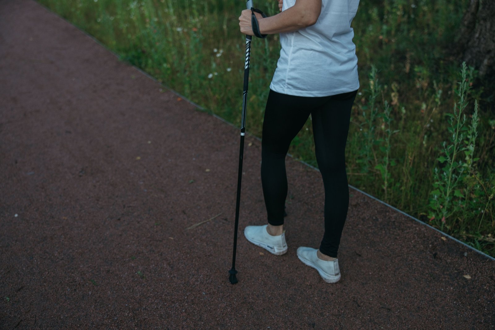 Traveler using a collapsible walking stick for support while hiking outdoors